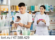 Attentive young guy choosing box of paracetamol antipyretic pills, scan QR code on label, positive young woman doctor helping. Стоковое фото, фотограф Яков Филимонов / Фотобанк Лори