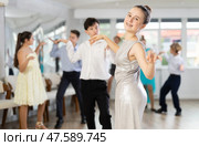 Teen girl in elegant evening dress dances incendiary twist with boy partner during choreography lesson. Стоковое фото, фотограф Яков Филимонов / Фотобанк Лори