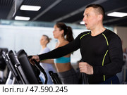 Strong sportsman training at elliptical machine in gym. Стоковое фото, фотограф Яков Филимонов / Фотобанк Лори
