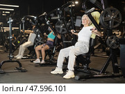 Elderly woman training on chest press machine in gym. Стоковое фото, фотограф Яков Филимонов / Фотобанк Лори