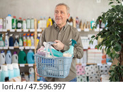 Senior man with filled basket household chemistry wanders around store, looking at display cases. Стоковое фото, фотограф Яков Филимонов / Фотобанк Лори