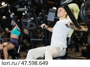Young man exercising on chest press machine in gym. Стоковое фото, фотограф Яков Филимонов / Фотобанк Лори