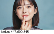 Smiling brightly, a Japanese woman points at her face in front of a blue backdrop, representing an Asian-inspired skincare routine and beauty concept. Стоковое AI-видео, аниматор Ирина Старикова / Фотобанк Лори