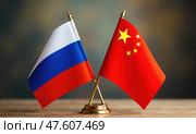 Национальные флаги России и Китая на деревянном столе. Символы стран крупным планом. Стоковое AI-изображение, AI-художник Илья Старков / Фотобанк Лори