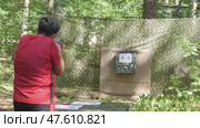 Closeup of woman with short hair in red t-shirt fires a rifle at shooting range target outside on summer day. Стоковое видео, видеограф Дмитрий Нечаев / Фотобанк Лори