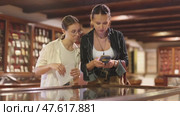Teen daughter and woman mother with phone walk around museum. Стоковое видео, видеограф Яков Филимонов / Фотобанк Лори