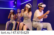 Cheerful young female friends wearing VR headsets and holding controllers having fun in virtual reality studio, competing in two-on-two shooter game. Стоковое видео, видеограф Яков Филимонов / Фотобанк Лори