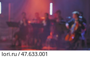 A breathtaking scene of musicians performing with violins and cello under bright, colorful lighting. The blurred view enhances the focused energy of the music being performed. Стоковое видео, видеограф Воловодов Владимир / Фотобанк Лори