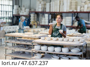 Girl ceramist arranging new bowls in workshop. Стоковое фото, фотограф Яков Филимонов / Фотобанк Лори