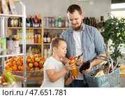 Boy with father scanning barcodes on bottles with juices with phone in supermarket. Стоковое фото, фотограф Яков Филимонов / Фотобанк Лори