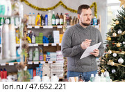 Male businessperson with paper document, plans to replenish restock stores inventory on Christmas Eve. Стоковое фото, фотограф Яков Филимонов / Фотобанк Лори