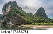 Picturesque mountains by the river. Green hills against the sky and clouds. The waves spread over the sandy shore. China. Li River. Li Jiang. Guilin. Стоковое фото, фотограф Вера Ивановна Кубарева / Фотобанк Лори