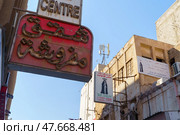 Manama, Bahrain - Jan 08 2024, panoramic view of facades of buildings with signages with inscriptions in Arabic on a narrow street, at daytime with a clear blue sky, without people, Manama, Bahrain. Редакционное фото, фотограф Сергей Богомяко / Фотобанк Лори