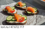 Smorrebrod - traditional Danish sandwiches. Black rye bread with salmon, cream cheese, capers on white background. Side view. Стоковое AI-видео, аниматор Ирина Старикова / Фотобанк Лори