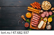 Gourmet Meat Assortment: A Culinary Composition with grilled sausages, salami and sauce, on a wooden board, for restaurant Menu. Стоковое AI-изображение, AI-художник Данила Большаков / Фотобанк Лори