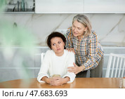 Middle-aged woman sitting at the kitchen-table and old woman trying to calm her down. Стоковое фото, фотограф Яков Филимонов / Фотобанк Лори
