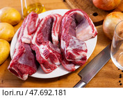 Raw beef ribs on board, potato tubers and whole onions. Стоковое фото, фотограф Яков Филимонов / Фотобанк Лори