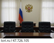 Российский герб и флаг в судебном зале, в котором вершится правосудие и торжествует закон, отражая принцип непредвзятости и честности. Стоковое AI-изображение, AI-художник Сергей Никифоров-Гордеев / Фотобанк Лори