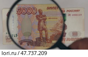 Рассматриваем с помощью лупы пятитысячную рублевую купюру. Понятие о финансах. Стоковое видео, видеограф Александр Собко / Фотобанк Лори