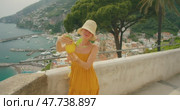 Woman holding giant Amalfi lemon with scenic coastline in the background. Стоковое видео, видеограф Igor Tichonow / Фотобанк Лори