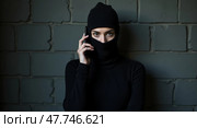Enigmatic androgynous figure in balaclava against gritty wall. Стоковое AI-изображение, AI-художник Андрей Бакусов / Фотобанк Лори