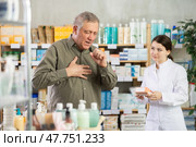 Senior man visits pharmacy and suffers from cough. Girl pharmacist offer help to sick customer. Стоковое фото, фотограф Яков Филимонов / Фотобанк Лори