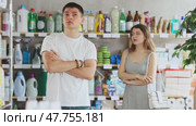 Young woman stands in a supermarket upset and resentful of a man who is standing in the background and talking emotionally. Couple quarrels in the hardware store. Стоковое видео, видеограф Яков Филимонов / Фотобанк Лори