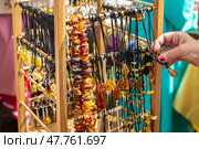 Amber beads in a street shop. The hand in the frame selects amber beads. Souvenir the Baltic Sea. Стоковое фото, фотограф Ольга Сейфутдинова / Фотобанк Лори