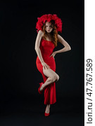 Woman posing with flair and emotion in a striking red dress and vibrant headpiece in a studio setting. Стоковое фото, фотограф Гурьянов Андрей / Фотобанк Лори