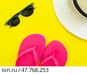 Flatlay, summer vacation. Straw hat, sunglasses and flip flops on a yellow background. Стоковое фото, фотограф Юлия Николаева / Фотобанк Лори