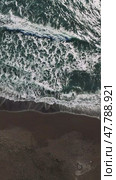 Aerial drone perspective revealing turquoise waves rhythmically breaking against dark sandy shoreline, generating hypnotic oceanic motion. Стоковое видео, видеограф ILIA GOROKHOV / Фотобанк Лори