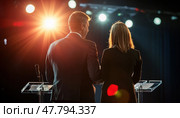 Two speakers presenting at a conference, standing at lecterns on stage. Стоковое AI-изображение, AI-художник Юрий Поздников / Фотобанк Лори
