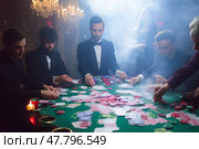 High-stakes poker game unfolds in elegant casino setting with gamblers engrossed in action at night. Стоковое AI-изображение, AI-художник Сергей Толмачёв / Фотобанк Лори