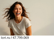 Laughing young woman with wind-blown hair in soft-lit white studio. Стоковое AI-изображение, AI-художник Максим Гребешков / Фотобанк Лори