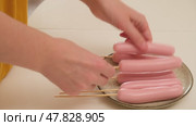 Person inserting wooden skewers into pink sausages on a ceramic plate. Studio food preparation shot. Cooking and homemade meal preparation concept. Стоковое видео, видеограф Андрей Журавлев / Фотобанк Лори