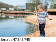 Summer lifestyle. A cute little boy is having fun playing with sand on the beach by the water. The concept of family entertainment and leisure. Стоковое фото, фотограф Photojuli / Фотобанк Лори