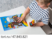 A little boy is playing with plasticine. Fine motor skills-developing games for children. The kid makes a horse. Useful games for child development. Стоковое фото, фотограф Photojuli / Фотобанк Лори