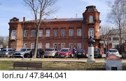 Main house of estate of merchant Zotov. Old brick building with annex on Dzerzhinsky Street, 11. Cars parked at historic city building. Kostroma, Russia, April 17, 2025. Редакционное фото, фотограф Ирина / Фотобанк Лори
