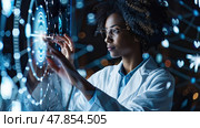 A woman in a lab coat examines a holographic interface, engaging with intricate visual data in an advanced research environment. Стоковое AI-изображение, AI-художник Данила Большаков / Фотобанк Лори