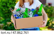 A Girl in plain colors T-shirt carries a box of recyclables. Стоковое AI-изображение, AI-художник Ирина Ручушкина / Фотобанк Лори