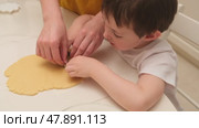 Child uses cookie cutter to cut out dough while learning to cook with mother. Kid aged three years (3 year old boy) Стоковое видео, видеограф Андрей Журавлев / Фотобанк Лори