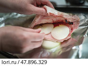 Stuffing gutted red fish with onion rings for cooking, showcasing a traditional seafood preparation technique. Стоковое фото, фотограф Татьяна Степанищева / Фотобанк Лори