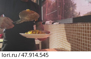 Tashkent, Uzbekistan - 9 20 2023: The chef puts carrots with a slotted spoon in a plate with rice from a large cauldron for pilaf. Редакционное видео, видеограф Aleksey Kidisyuk / Фотобанк Лори