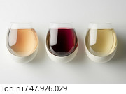 Different Varieties of Wine Showcased in Elegant Stemless Glasses on a Clean White Backdrop. Стоковое AI-изображение, AI-художник Юлия Гапеенко / Фотобанк Лори