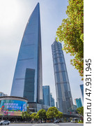 Shanghai, China - 1 April 2025: Futuristic Pudong skyline featuring Shanghai World Financial Center and Jin Mao Tower with bustling streets below on a sunny day. Редакционное фото, фотограф Татьяна Терехина / Фотобанк Лори