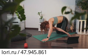 Focused woman performs push-ups, stretching on yoga mat surrounded by smart tech and plants. Active wellness, mindful training in comfortable home environment reflect new era health-conscious living. Стоковое видео, видеограф Енваев Андрей / Фотобанк Лори