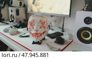 Close-up of expressive mask on stylish workspace. Idea of hidden identity, digital lifestyle, and streaming culture. Great for content about cyber world, for gamers, streamers and online persona. Стоковое видео, видеограф Енваев Андрей / Фотобанк Лори