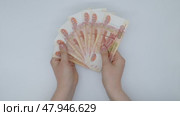Hands showing five thousand dollar bills holding them in a fan on a white background, top view. Стоковое видео, видеограф Катерина Белякина / Фотобанк Лори