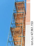 Фасад здания с установленными строительными лесами. Building under construction in scaffolding around the house for cement plastering work on the high outer wall. Стоковое фото, фотограф Татьяна Д / Фотобанк Лори