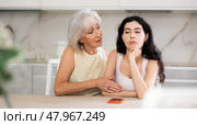 Elderly mother asks for forgiveness from her adult daughter and calms her down after a domestic quarrel in kitchen. Стоковое фото, фотограф Яков Филимонов / Фотобанк Лори